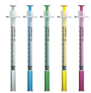 Five syringes with colored liquids (gray, blue, green, yellow, and pink) lined up in a row on a white background.