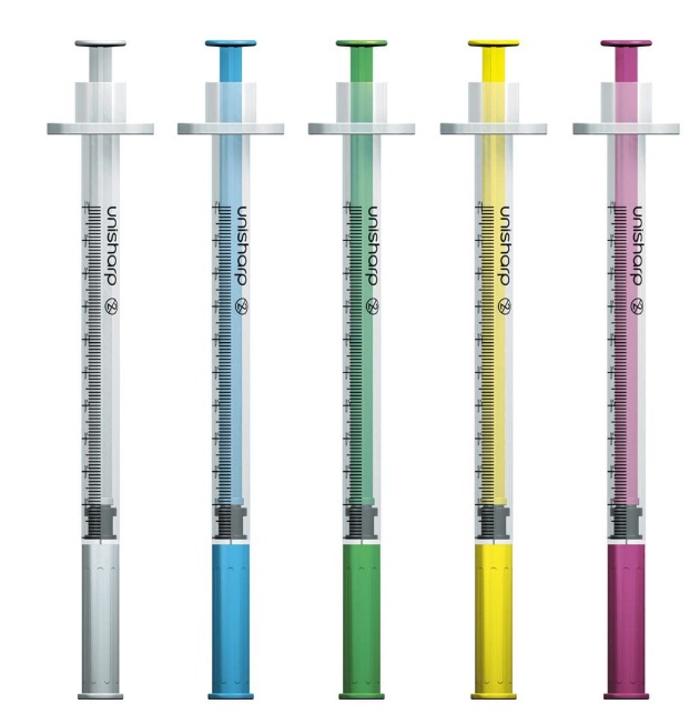 Five syringes with colored liquids (gray, blue, green, yellow, and pink) lined up in a row on a white background.