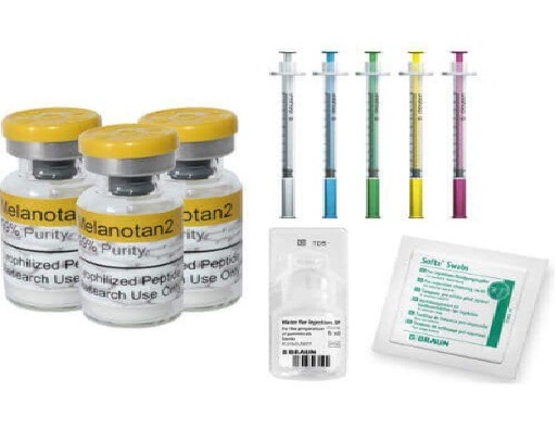 Three yellow-capped vials next to color‑coded syringes and diagnostic kit components on a white background.